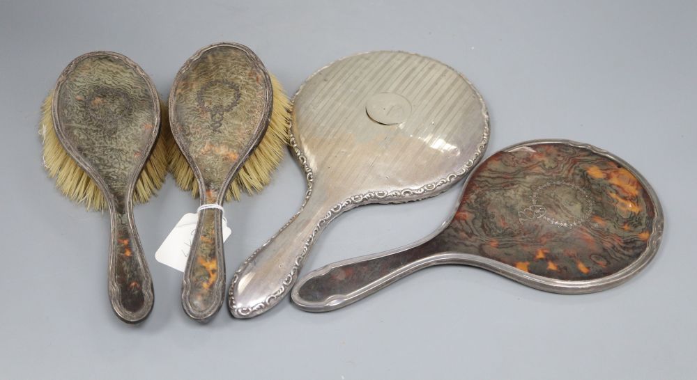 A three piece silver and tortoiseshell backed dressing table set, inset wreath pattern comprising: two hair brushes and a hand mirror,